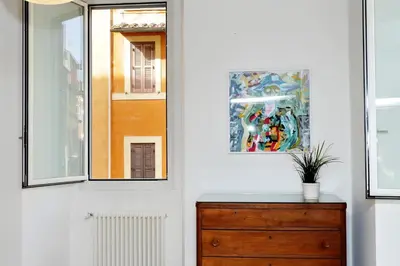 a room with a dresser and two windows at Giulia Charme - My Extra Home in Rome