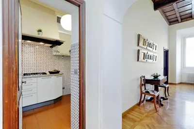 a kitchen with white cabinets and a table with a chair at Giulia Charme - My Extra Home in Rome
