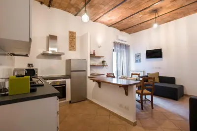 a kitchen and living room with a table and a couch at Castro Pretorio Cozy apartment in Rome