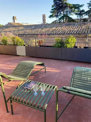 two green chairs and wine glasses on a patio at Colosseo Esclusivo attico con terrazze private in Rome