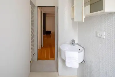 a white bathroom with a sink and a hallway at Via G. Ferrari Private Apartment in Rome