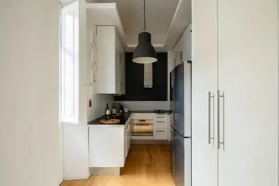 a kitchen with white cabinets and a black refrigerator at Via G. Ferrari Private Apartment in Rome