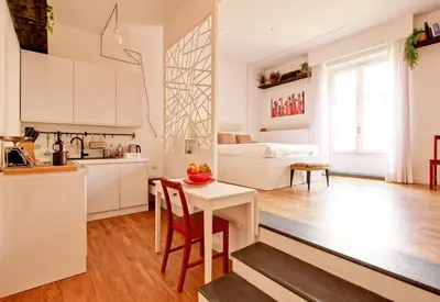 a white kitchen and living room with a table and chairs at Marte in Trevi in Rome