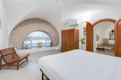 a bedroom with a bed and a chair and a window at Fori Imperiali Luxury Apartment in Rome
