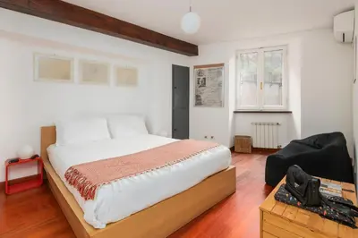 a bedroom with a large bed and a chair at Trastevere Zen Home-ZENO 33 in Rome