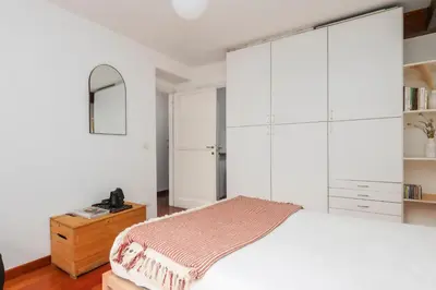 a bedroom with a large white bed and a wooden dresser at Trastevere Zen Home-ZENO 33 in Rome