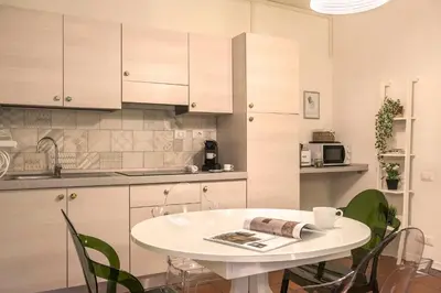 a kitchen with a white table and green chairs at Nettuno Apartment in Rome