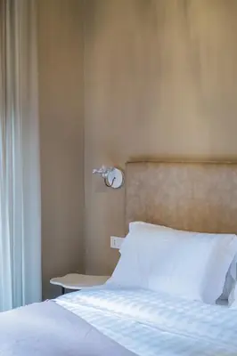 a bedroom with a bed with white sheets and a lamp at 163 BOUTIQUE HOTEL in Rome