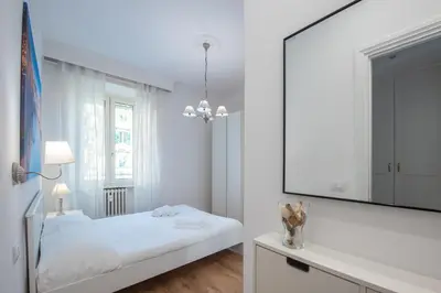 a white bedroom with a large mirror and a bed at Benny Gold - Elegant apartment right next to the METRO in Rome