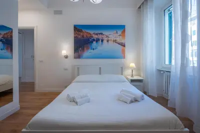 a white bedroom with a large white bed with two pillows at Benny Gold - Elegant apartment right next to the METRO in Rome