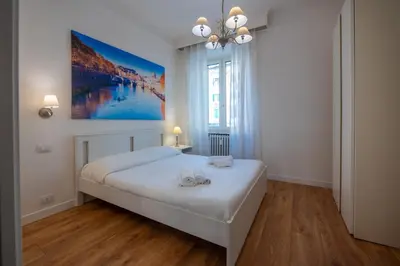 a bedroom with a large white bed and a painting on the wall at Benny Gold - Elegant apartment right next to the METRO in Rome