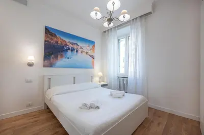 a white bedroom with a bed with two slippers on it at Benny Gold - Elegant apartment right next to the METRO in Rome