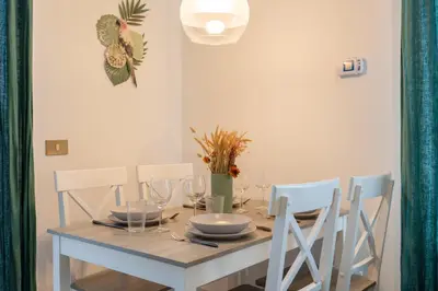 a dining room table with white chairs and a wooden table with glasses at St.Peter station Holiday apartment in Rome