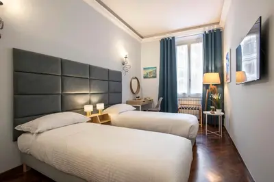 two beds in a hotel room with blue curtains at Montebello Style in Rome