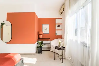 a bedroom with an orange wall and a mirror at Maison Lumiere, Design Apt 5 min from Tiburtina Station in Rome