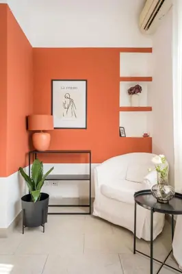 a bedroom with an orange accent wall at Maison Lumiere, Design Apt 5 min from Tiburtina Station in Rome