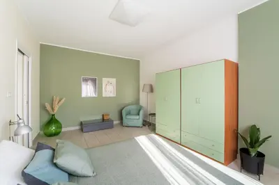 a bedroom with a green cabinet and a blue chair at Maison Lumiere, Design Apt 5 min from Tiburtina Station in Rome