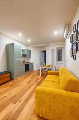a living room with a yellow couch and a kitchen at Home Trastevere.62 in Rome