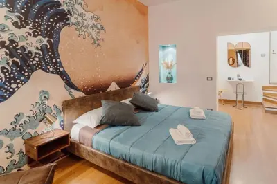a bedroom with a blue bed and a painting on the wall at La Grande Onda (Trastevere) in Rome