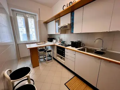 a kitchen with white cabinets and a sink and counters at Trastevere Monteverde Velia House in Rome