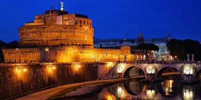 a building with a bridge and a castle at night at Vatican's Roof in Rome