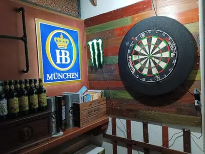 a dart board on a wall next to bottles of beer at Corona House in Rome