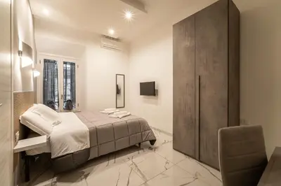 a bedroom with a large bed and a chair at TERMINI HOLIDAY in Rome