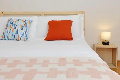 a white bed with a red pillow on it at Monteverde family apartment in Rome