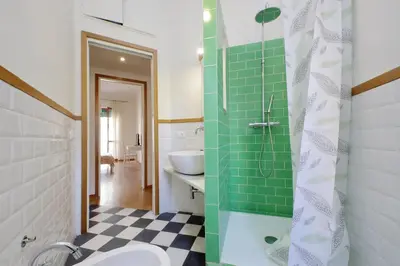 a bathroom with a sink and a shower with green tiles at Monteverde family apartment in Rome