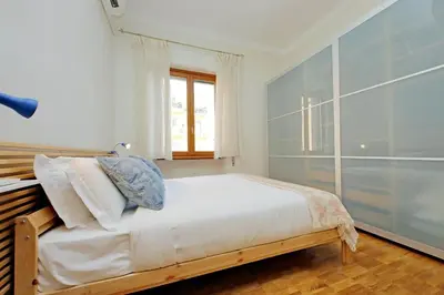 a bedroom with a bed with white sheets and a window at Monteverde family apartment in Rome