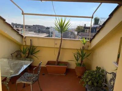 a balcony with potted plants and a table and chairs at Trastevere Lenci House in Rome
