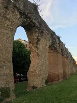 an old brick wall with an arch in the grass at Domus Felix Rome in Rome
