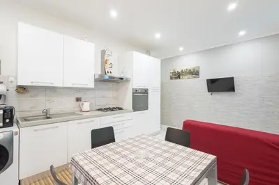 a kitchen with white cabinets and a table with a red couch at Domus Felix Rome in Rome