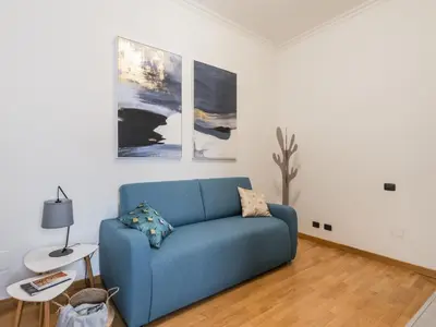 a blue couch in a living room with paintings at The Best Rent - Three-bedroom apartment near Piazza Barberini in Rome