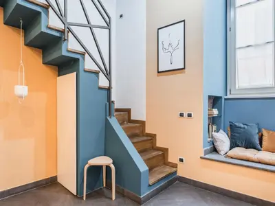 a staircase in a house with a stool and a window at The Best Rent - Colorful loft in Trastevere area in Rome