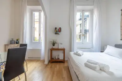 a white bedroom with a bed and a chair at Saturno in Trevi in Rome