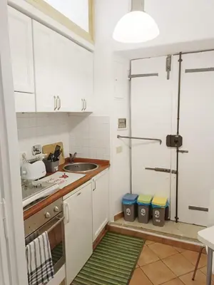 a kitchen with white cabinets and a green rug at Marcello Apartament in Rome