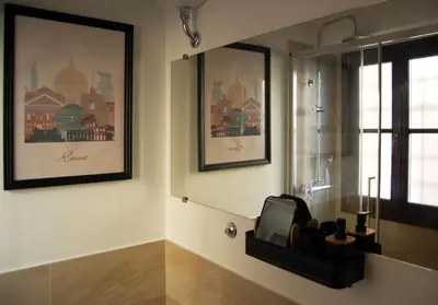 a bathroom with two pictures on the wall and a window at Grottino 3a Apartment in Rome