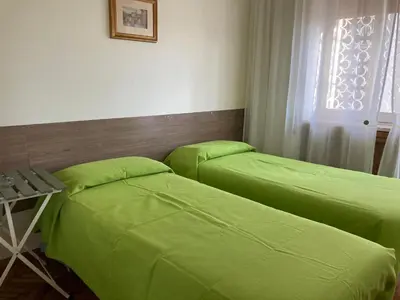 two beds in a room with green sheets at Le Mille e Una Notte in Rome