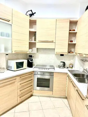 a kitchen with wooden cabinets and a stove and a microwave at 15 Min. Colosseo 2 - Casa di Micca in Rome