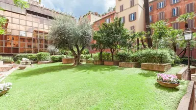 a courtyard with a lawn with a tree and buildings at Giove in Trevi in Rome