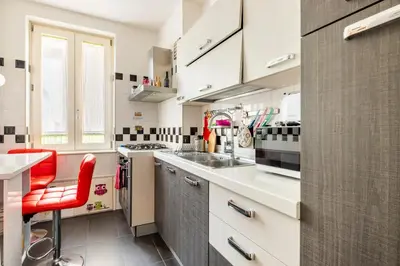 a kitchen with white cabinets and a red chair at Comfortable apartment Via Appia - B in Rome