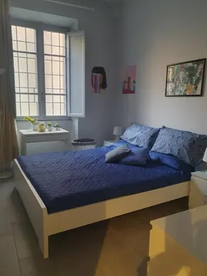 a bedroom with a bed with a blue comforter at House Cocò in Rome