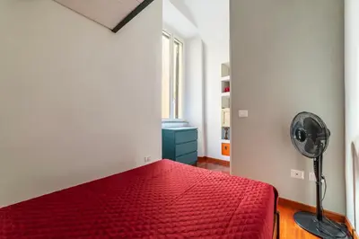 a bedroom with a red bed and a fan at GuestHost - San Giovanni in Laterano Dazzling Apartment in Rome