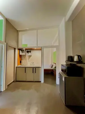 a kitchen with white cabinets and a room with a bed at JEF Apartments San Giovanni by Hostand in Rome