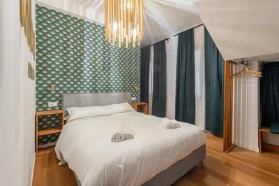 a bedroom with a large white bed with a chandelier at Koba Rooms Nomentano in Rome