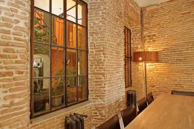 a dining room with a wooden table and a brick wall at Piscinula in Rome