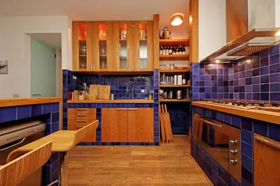 a kitchen with blue tiled walls and wooden cabinets at Piscinula in Rome