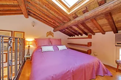 a bedroom with a large pink bed with wooden ceilings at Spagna in Rome