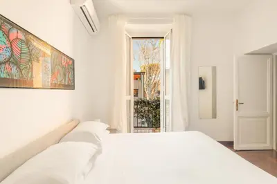 a white bedroom with a white bed and a window at Vatican Lovely 2BR Apartment with Terrace in Rome